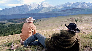 two men wearing cowboy hats lying on grass field during daytime HD wallpaper