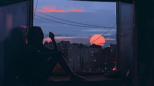 woman sitting beside window with view of sunset