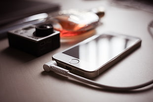silver iPhone 5s beside silver action camera HD wallpaper