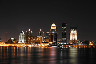 city skyline during nightime in front of placid body of water, louisville