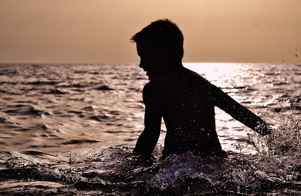boy playing in the sea during dusk HD wallpaper