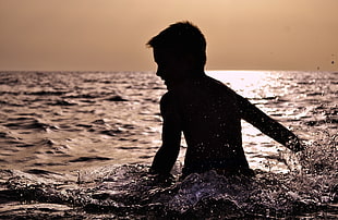 boy playing in the sea during dusk HD wallpaper