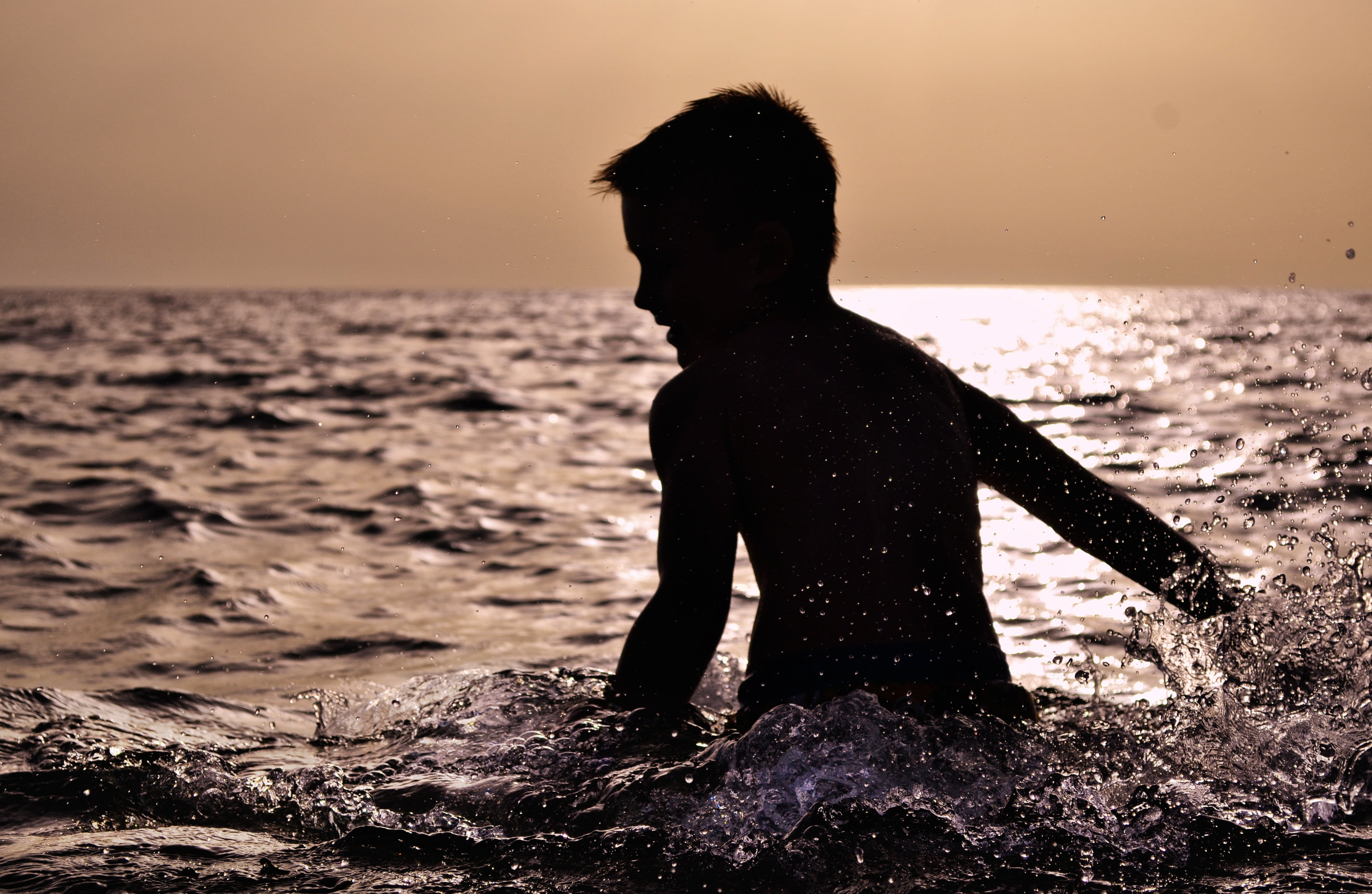 boy playing in the sea during dusk