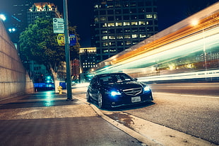 timelapse photography of black Acura TL parked on concrete road near concrete building