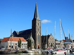 brown church near dock with boats HD wallpaper