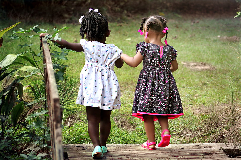 toddler's wearing white and black-and-pink dress walking on brown wooden bridge photography HD wallpaper