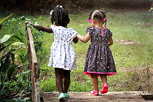 toddler's wearing white and black-and-pink dress walking on brown wooden bridge photography
