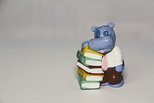 hippo in shirt beside books figurine