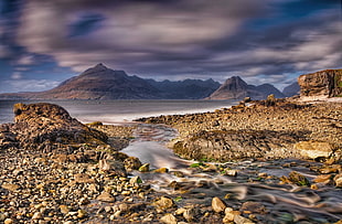 time lapse photo of rocky mountains and river under white clouds and blue skies, elgol
