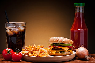 burger with fries on plate beside soda on drinking glass and ketchup bottle