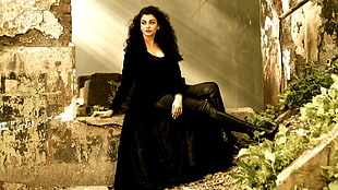 woman in black dress sitting on brown rock