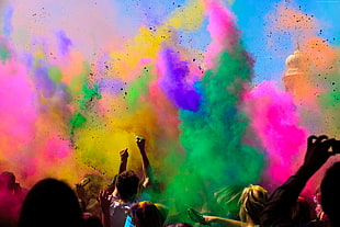 people throwing pink, green, and blue Holi powders
