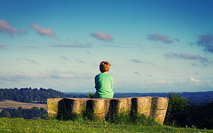 boy sitting on concrete hillside bench HD wallpaper