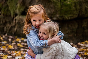 female toddlers hugging each other near stone
