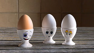 three egg figurines on gray wooden surface