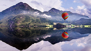 red and blue hot air balloon floating near a moutain