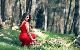 woman in red dress picking apples on basket