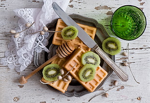 kiwi fruit and honey dipper on gray plate