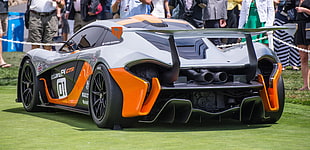 black and orange sports car near group of people