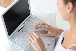 woman in white top holding white laptop