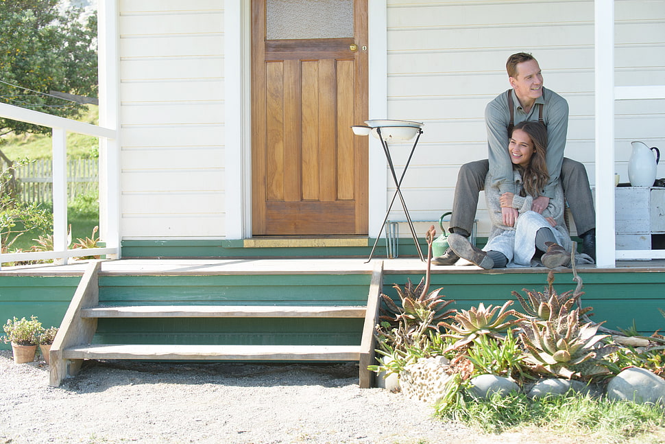 teal and white wooden house with man and woman posing HD wallpaper