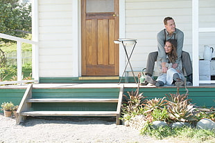 teal and white wooden house with man and woman posing