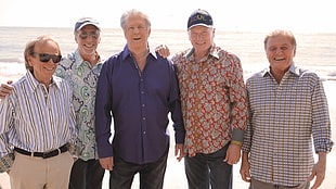 five men standing on beach shore during daytime HD wallpaper