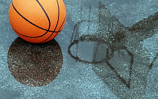 orange and black basketball on gray concrete floor covered with water