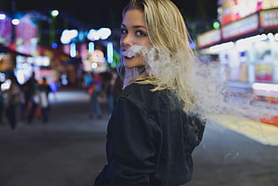 close up photograph of woman with smoke in mouth in street