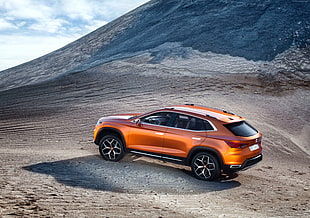 orange SUV on brown soil near mountain