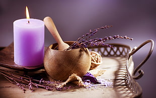 close up photography mortar pestle beside purple pillar candle