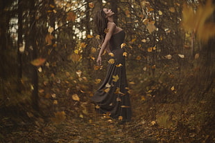 woman wearing black maxi dress standing in the middle of forest during sunset