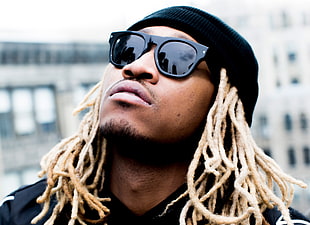 man with blonde dreadlocks wearing sunglasses and knitted cap