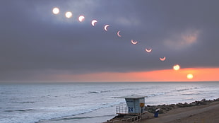 white lifeguard house, solar eclipse, sea, horizon, sky