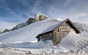 gray wooden house near mountain during snow time photo