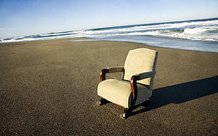 brown leather-padded wooden chair beside sea