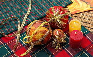 two red and orange pillar candles beside baubles
