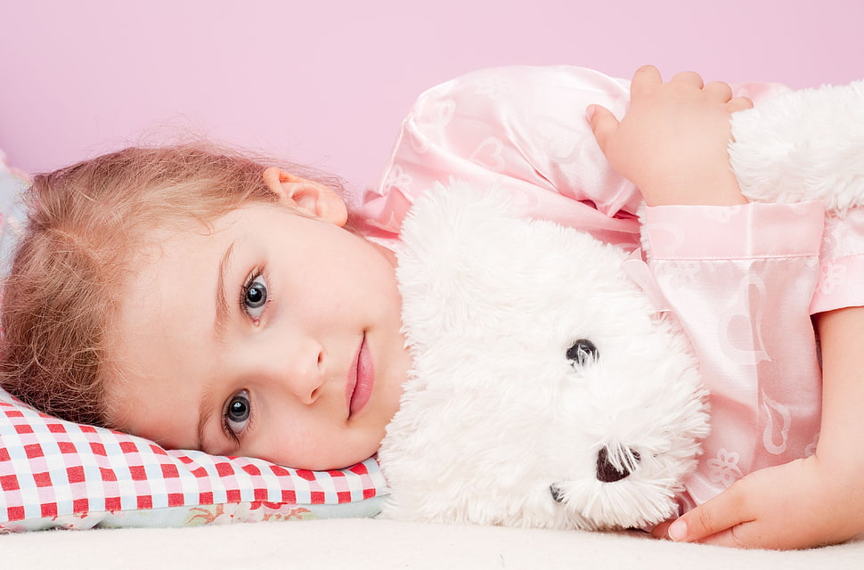 girl wearing pink long-sleeve shirt hugging white dog plush toy HD wallpaper