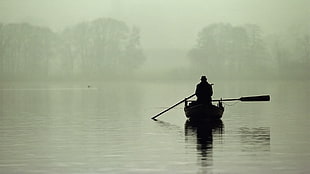 silhouette photography of man riding on canoe