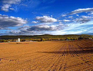 brown farm land under the cloudy sky during daytime