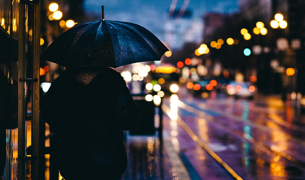 person in black jacket holding umbrella at nighttime HD wallpaper
