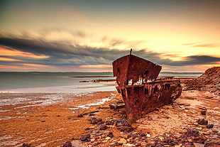 rusted boat washed out off shore near water