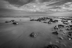 gray-scale photo of beach with rocks