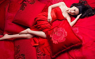woman wearing red strapless dress lying on bed