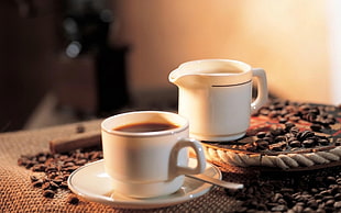 two white ceramic tea cups with coffee beans