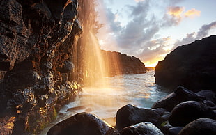 waterfalls near the sea under gray sky at daytime