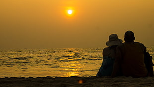 Man and woman sitting in beach side during dusk, goa, india