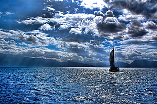 black sailing boat under cumulus clouds on body of water HD wallpaper