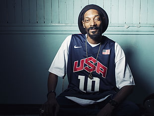 Snoop Dogg in black USA 10 nike jersey shirt next to white wall