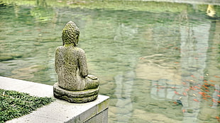 gray Budha statue with large body of water
